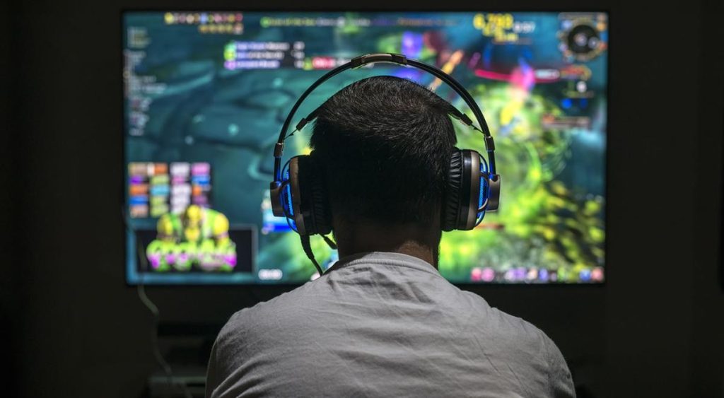 Joueur utilisant une manette devant un écran affichant un jeu vidéo