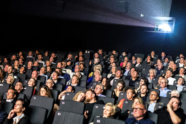 Spectateurs installés dans une salle de cinéma devant un grand écran